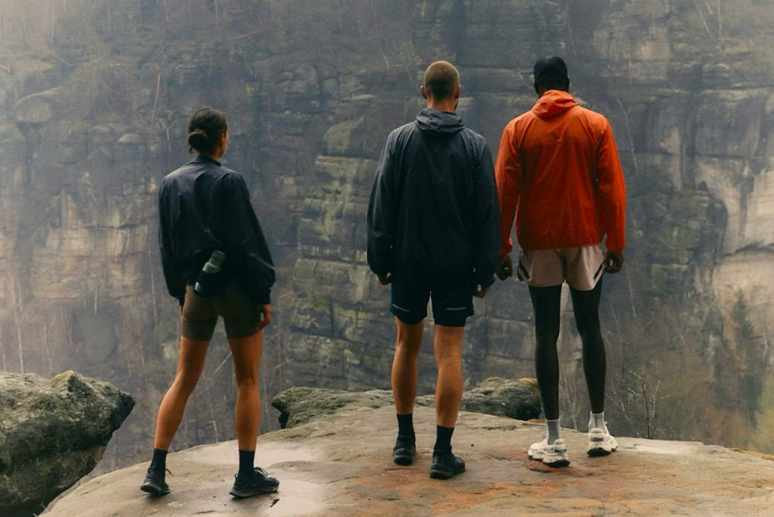 three hikers overlooking a mountain from a cliff